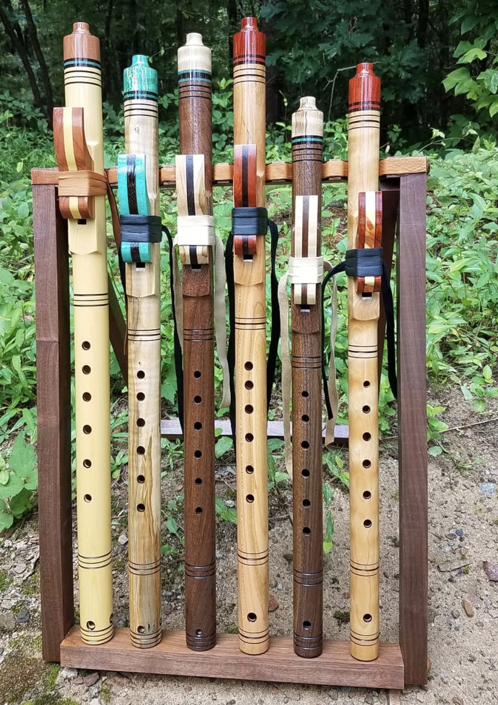 Six wooden flutes, maple and walnut with turquoise accents standing upright
